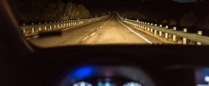 Small car driving down a dark road at night