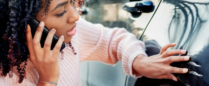 Woman inspecting dent in her car