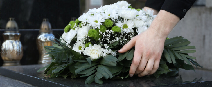 A woman lays flowers on a coffin