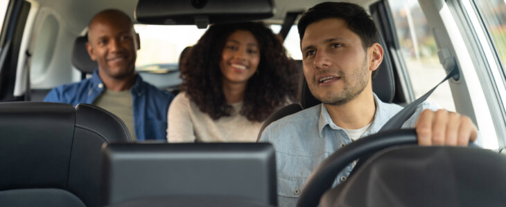 Rideshare driver talking to a couple while driving them to their destination - mobility as a service concepts